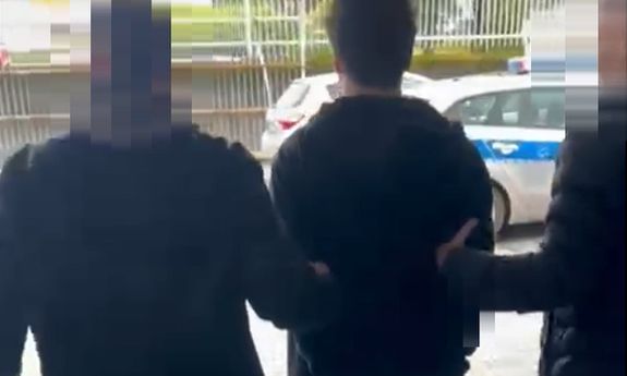 dwaj nieumundurowani policjanci prowadzą zatrzymanego mężczyznę
