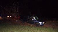 Na zdjęciu widać uszkodzony samochód osobowy. W tle samochód i drzewa.