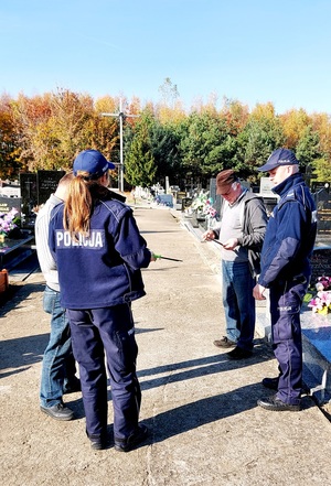 policjanci rozdają odblaski na cmentarzu
