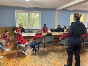 Policjantki z dziećmi, dziećmi w czerwonych bluzach z napisem Akademia Małego Strażaka, wspólne zdjęcie policjantek z dziećmi.