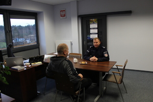 Mężczyzna wraz z Komendantem Powiatowym siedzą przy stole w pokoju Komendanta.