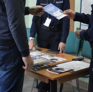 dzielnicowy wręcza zainteresowanemu ulotkę