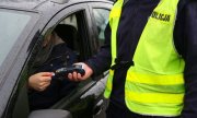 Na zdjęciu widać umundurowanego policjanta, który trzyma w ręku terminal płatniczy oraz kierowcę samochodu osobowego opłacającego kartą płatniczą nałożony MKK.