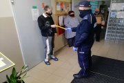 Umundurowany policjant przekazuje element odblaskowy podopiecznemu Powiatowego Środowiskowego Domu Samopomocy Społecznej w Pęczniewie.