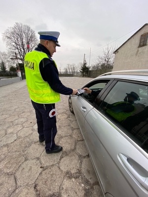 Policjant wręcza kierującemu ulotkę dotyczącą zmian w przepisach ruchu drogowego.