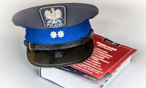 policyjna czapka leży na kodeksie przepisów