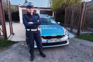 st.post. Natalia Grzeszkiewicz stoi przy oznakowanym radiowozie policyjnym