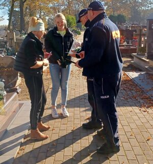 policjanci rozdają odblaski na cmentarzu