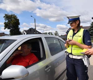 policjantka przy samochodzie kierowcy, który zjada cytrynę