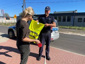 Policjant rozdający elementy odblaskowe.