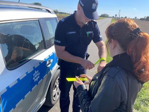 Policjant rozdający elementy odblaskowe.