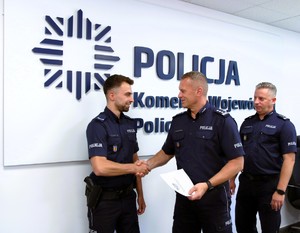 Policjant odbiera nagrodę od Komendanta.