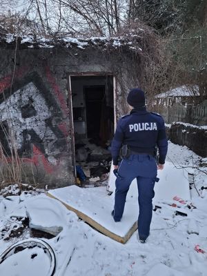 Policjant przed wejściem do pustostanu.