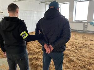 policjant z zatrzymaną osobą, na podłodze krajanka tytoniowa,pomieszczenie na hali