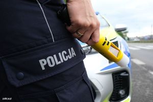 Policjant trzymający w dłoni urządzenie do badania stanu trzeźwości.