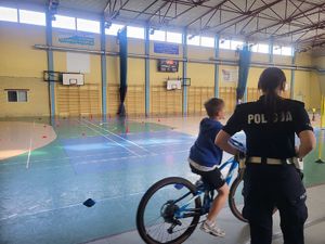 Policjantka obserwująca dzieci pokonujące tor przeszkód.