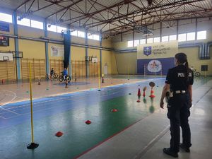 Policjantka obserwująca dzieci pokonujące tor przeszkód.