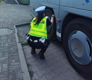 Policjantka sprawdza stan ogumienia autokaru.