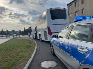 Radiowóz i zaparkowany przed nim autokar.