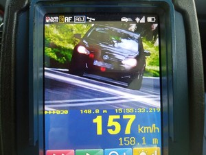 Zdjęcie z urządzenia do pomiaru prędkości. Na zdjęciu widoczny pojazd i liczba  157 km/h.