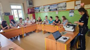 Policjantka na spotkaniu z rodzicami prezentująca walizkę edukacyjną.