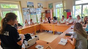 Policjantka na spotkaniu z rodzicami prezentująca walizkę edukacyjną.