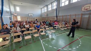 Policjantka na spotkaniu z rodzicami prezentująca walizkę edukacyjną.