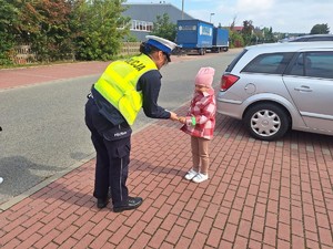 Policjantka wręczająca odblask dziecku.