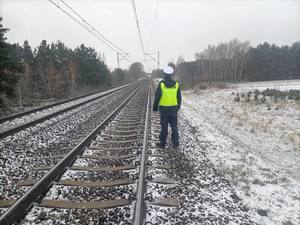 Policjanci w kamizelkach odblaskowych przy torach.