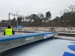 Policjanci w kamizelkach odblaskowych przy torach.