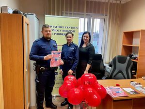 Policjanci w pokoju, obok nich czerwone balony.