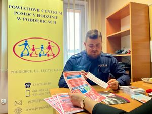 Policjanci w pokoju, obok nich czerwone balony.