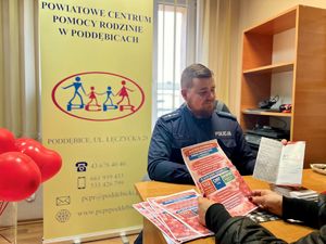 Policjanci w pokoju, obok nich czerwone balony.