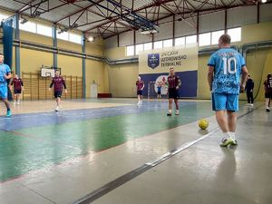 Zawodnicy grający w piłkę na hali sportowej.