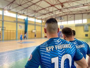 Zawodnicy grający w piłkę na hali sportowej.