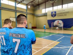 Zawodnicy grający w piłkę na hali sportowej.