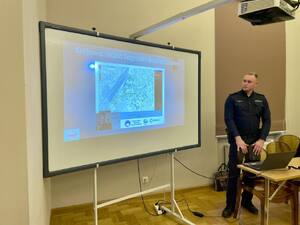 Seniorzy na debacie społecznej, w tle prelegenci.