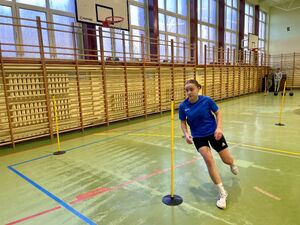Uczniowie na hali sportowej pokonują tor przeszkód.
