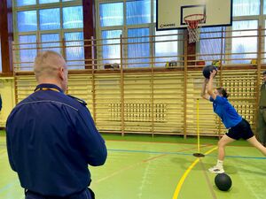 Uczniowie na hali sportowej pokonują tor przeszkód.