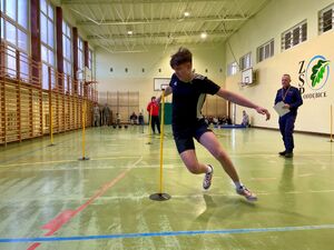 Uczniowie na hali sportowej pokonują tor przeszkód.