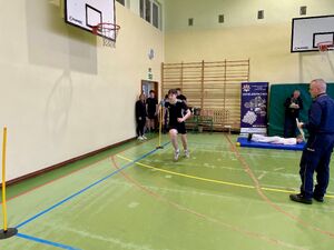 Uczniowie na hali sportowej pokonują tor przeszkód.