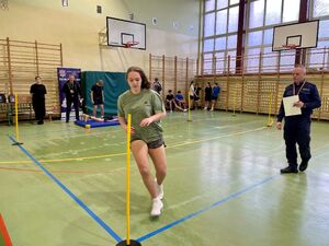 Uczniowie na hali sportowej pokonują tor przeszkód.