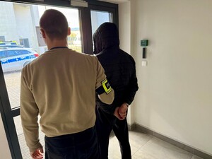 Zatrzymany mężczyzna z policjantem stojącym obok.