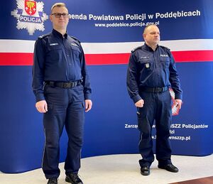 Umundurowani funkcjonariusze stojący obok siebie na sali konferencyjnej.