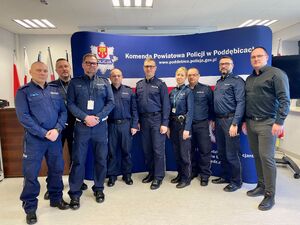 Umundurowani funkcjonariusze stojący obok siebie na sali konferencyjnej.