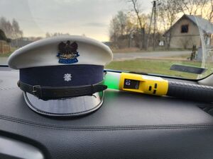 Zdjęcie przedstawiające czapkę policyjną, obok urządzenie do pomiaru stanu trzeźwości.