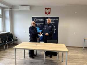 Panowie Komendanci za biurkiem podpisują dokument.