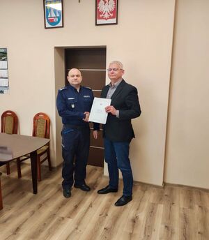 Wspólne zdjęcie Komendanta i Wójta, panowie trzymają dłoń w uścisku.