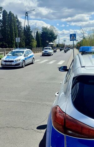 Policyjny radiowóz, w tle parada motocykli.