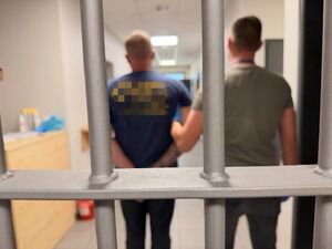 Zatrzymani trzymani przez nieumundurowanych policjantów.